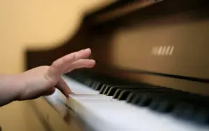 A hand plays a key on a classic grand piano | Private piano lessons at Cavod in Lancaster PA