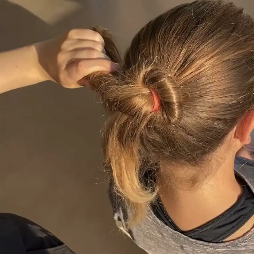 A ballet dancer from Cavod Performing Arts having her second ponytail section of hair wrapped around the other ponytail section.