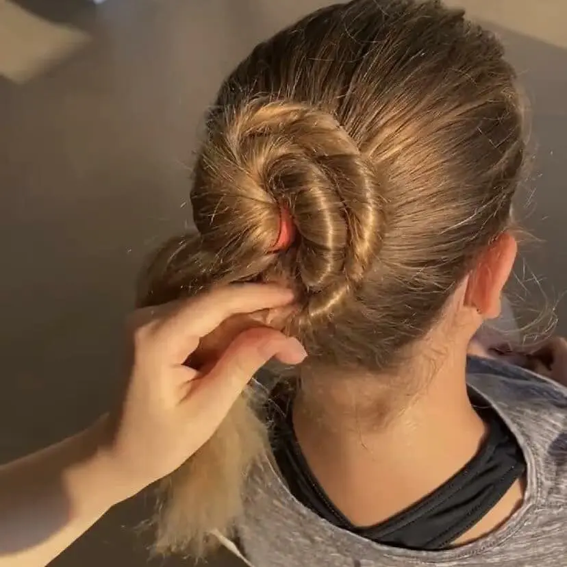 A woman adjusting a Cavod ballet dancer's ponytails to make a ballet bun.
