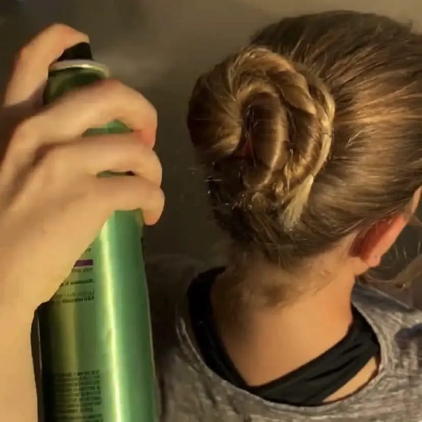 A woman using bobby pins and hairspray to preserve a ballet dancer's ballet bun at Cavod Performing arts in New Holland , PA.