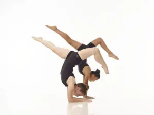 Two dance students from Cavod Performing Arts balancing while doing a tilted handstand.