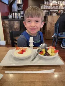 A child smiling while eating dessert.