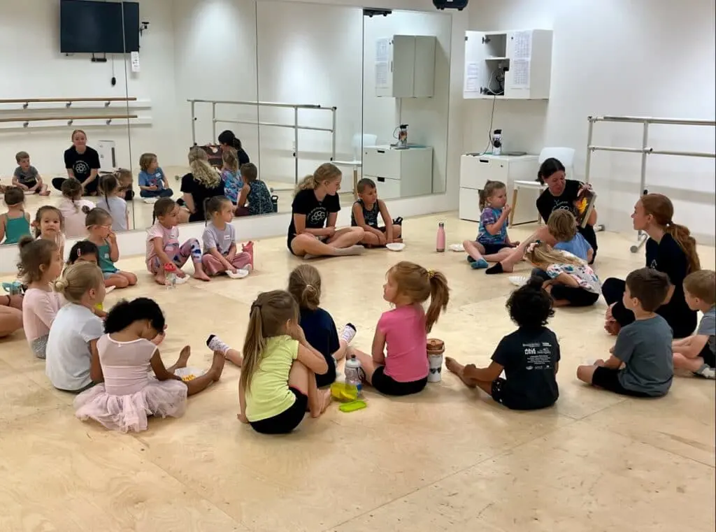 Children sitting and snacking during a break at Cavod's Around The World summer camp | Cavod Performing Arts