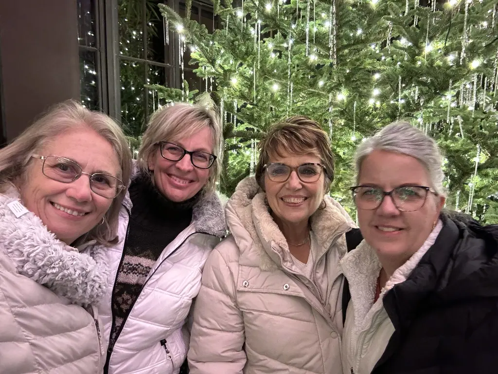 Cavod's Executive Director Connie Dienner and her friends posing for a picture in front of a Christmas tree at Longwood Gardens.