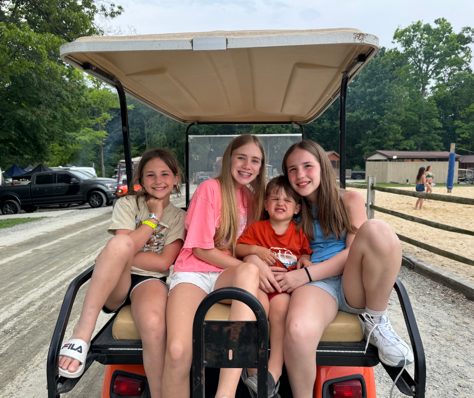 Children sitting in a golf cart at a campground
