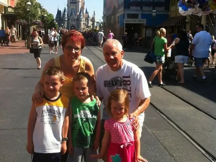 Cavod's Connie Dienner and her husband posing for a picture in Disney with their young grand children