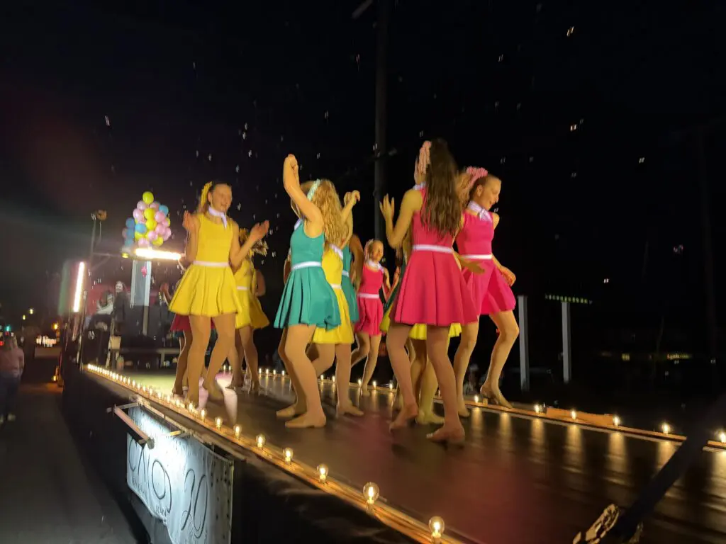 Side view of the Cavod Performing Arts float featuring dancers performing routines.