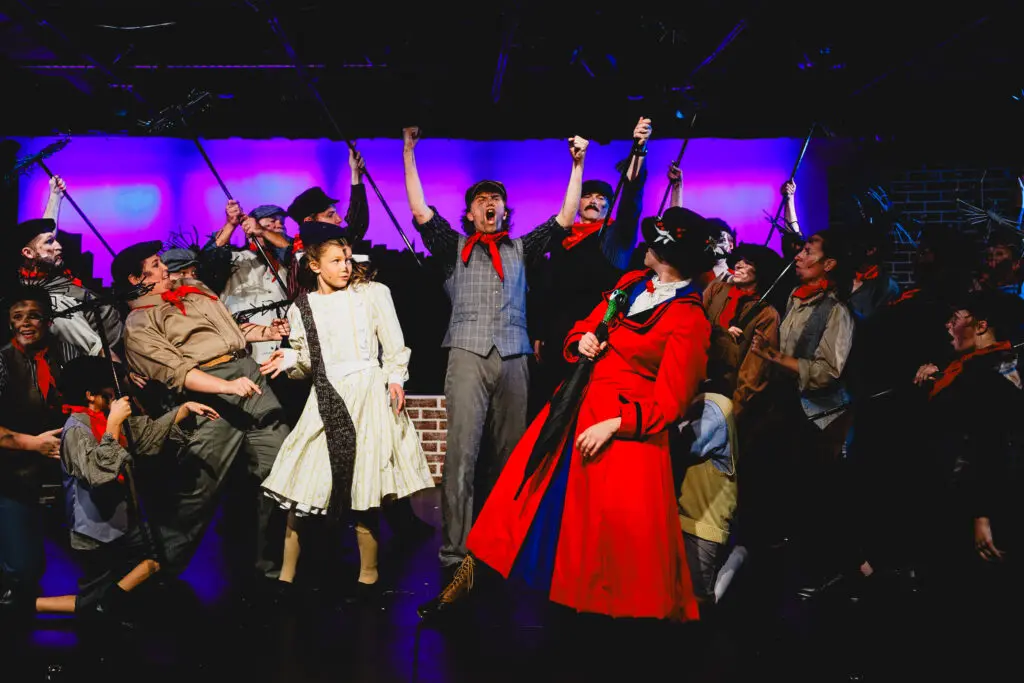 Sophia Grado as Mary Poppins in a charming pose on the Cavod Theatre stage, dressed in classic Mary Poppins attire.