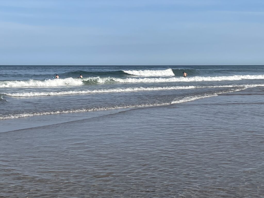 A photo of the surf, with mid sized waves crashing on the shore