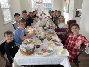 Relatives of a Cavod employee sitting together and smiling at a long dinner table on Christmas Eve. 