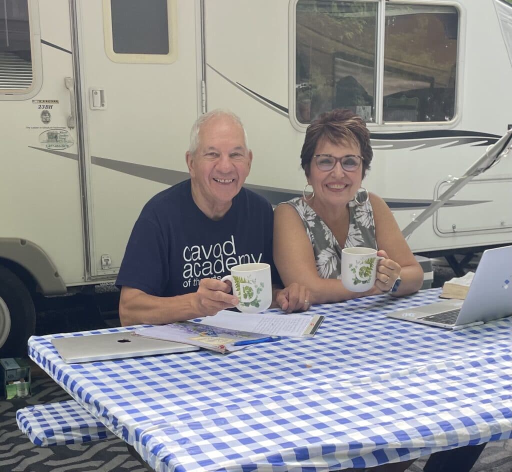 Cavod Performing Art's founder Connie Dienner sitting and having coffee with her husband while sitting next to an RV. 